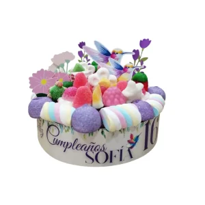 Tarta de golosinas personalizada de 20 cm de diámetro, decorada con nubes, flores de Bulgari y gominolas variadas, envuelta en celofán para regalo.